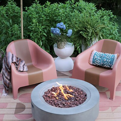 Un patio extérieur avec une terrasse peinte et un foyer circulaire moderne au centre.